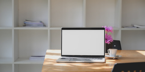 Open blank screen laptop computer in comfortable workspace with pink flower