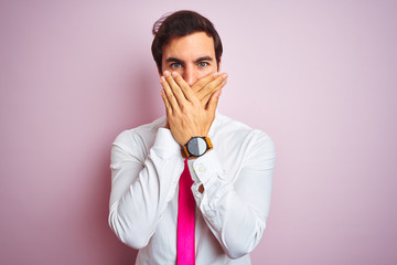 Young handsome businessman wearing shirt and tie standing over isolated pink background shocked covering mouth with hands for mistake. Secret concept.