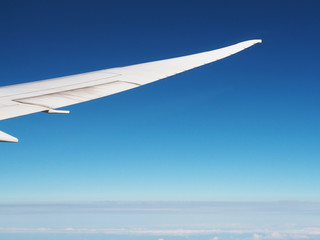 Wing of airplane flying against blue sky