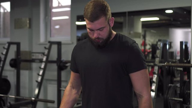 A man is training with small dumbbells in the gym.