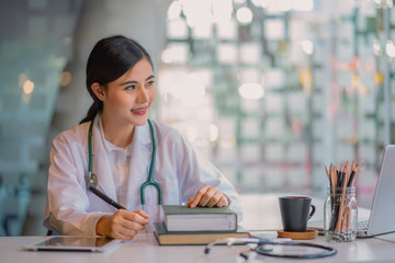 Female doctor working at office desk and smiling.