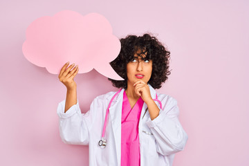 Young arab woman with curly hair holding cloud speech bubble over isolated pink background serious face thinking about question, very confused idea
