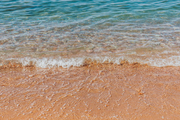 Turquoise sea waves splashing on pebble shore