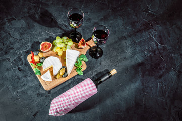 Antipasto platter with ham, prosciutto, salami, blue cheese, mozzarella, olives, grissini bread sticks with pesto and red wine on a dark background