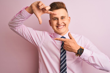 Young handsome businessman wearing shirt and tie standing over isolated pink background smiling making frame with hands and fingers with happy face. Creativity and photography concept.