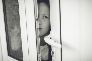 Scared girl kid in opened door. Safety concept