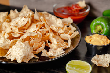 plate with taco, nachos chips and tomato dip. Spicy Nachos (close-up shot) on rustic wooden background
