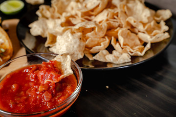 plate with taco, nachos chips and tomato dip. Spicy Nachos (close-up shot) on rustic wooden background