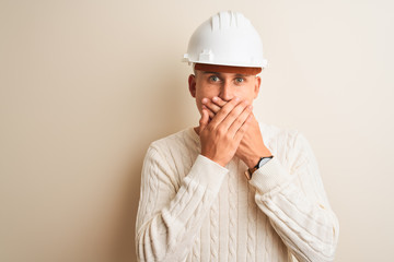 Handsome architect man wearing security helmet standing over isolated white background shocked covering mouth with hands for mistake. Secret concept.