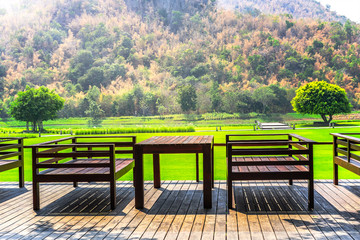 Empty wooden table with natural mountain landscape and green grass field background 