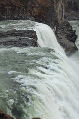 A three-step staircase of the Gullfoss waterfall on Hvita river, as pictured in detail (water plunging into the canyon, mossy cliffs, thick spray, panorama of the rapids)
