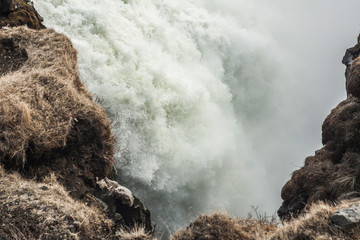 A three-step staircase of the Gullfoss waterfall on Hvita river, as pictured in detail (water plunging into the canyon, mossy cliffs, thick spray, panorama of the rapids)