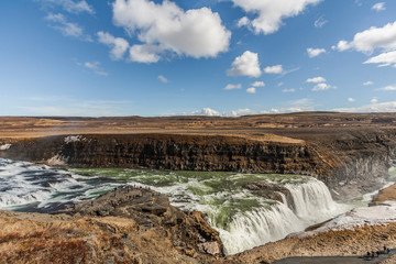 A three-step staircase of the Gullfoss waterfall on Hvita river, as pictured in detail (water plunging into the canyon, mossy cliffs, thick spray, panorama of the rapids)