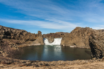 Basalt rock formations and lava columns and arches of Hjálparfoss waterfall (part of Fossá rivera) in south Iceland