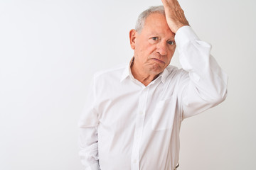 Senior grey-haired man wearing elegant shirt standing over isolated white background surprised with hand on head for mistake, remember error. Forgot, bad memory concept.