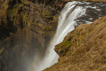 Waterfall Skogafoss (part of Skoga river taking its origin in the Highlands of Iceland) pictured with rainbow due to spray the waterfall produces