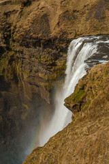 Waterfall Skogafoss (part of Skoga river taking its origin in the Highlands of Iceland) pictured with rainbow due to spray the waterfall produces