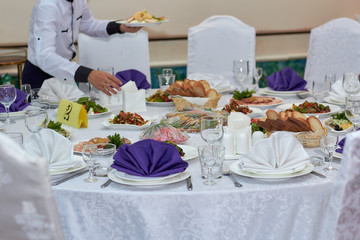 Delicious table with food, waiter's hand, dishes, restaurant.