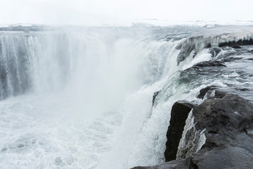 Selfoss waterfall (part of Jökulsá á Fjöllum river in the north of Iceland originating from Vatnajokull glacier) in winter, pictured with snow icicles, snow patterns and spray over the stream 
