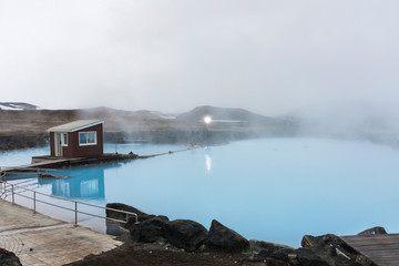 Smoke sliding over bluish hot waters of the Blue Lagoon, a geothermal spa in the lava field near Grindavik on the Reykjanes Peninsula in Iceland as captured in an afternoon mist