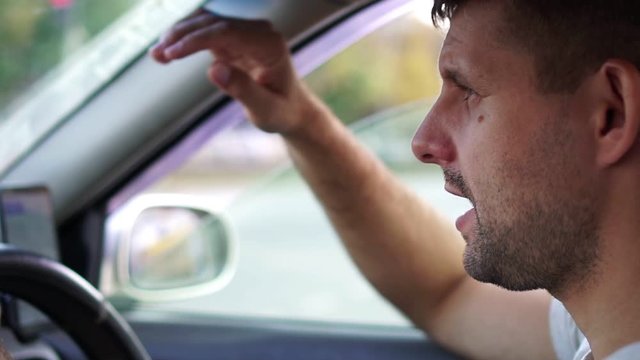 male driver is angry and swears due to traffic congestion. Traffic jams, angry driver.