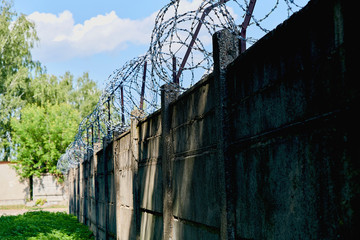 Old concrete fence with barbed wire. Protection and security of the external perimeter of the territory.