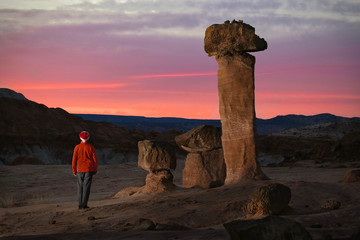 Fototapeta na wymiar Man hiker by the giant rock toadstools watching sunset in Arizona. Page. Arizona. United States of America