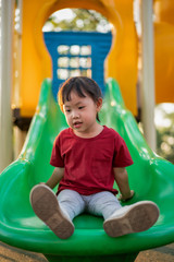 Fototapeta na wymiar Asian baby girl playing slider at playground in the park..