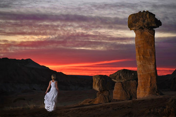 Fototapeta na wymiar Woman in white dress standing by giant sandstone toadstools in rock desert near Page. Arizona. United States of America