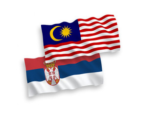National vector fabric wave flags of Serbia and Malaysia isolated on white background. 1 to 2 proportion.