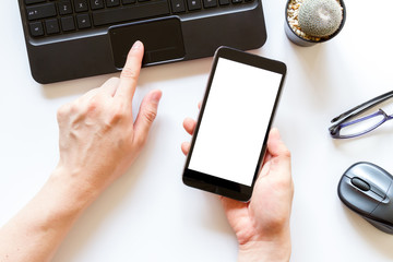 hand using computer and mobile phone with blank screen on office desk