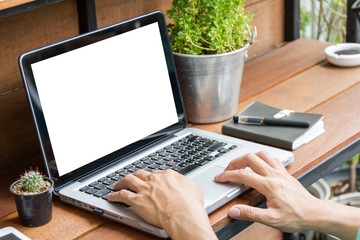man using laptop computer with blank screen on wooden table