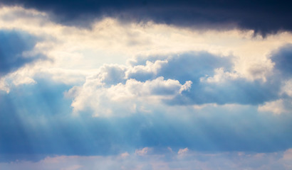 The sun rays through dark clouds at sunset_