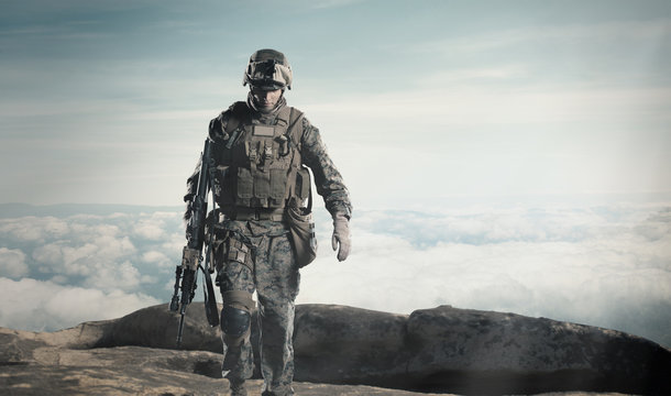 Soldier with a rifle. Steps against clouds.