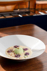 Fancy ice cream dessert with a scoop of pistachio ice cream, plums, almonds and creamy sauce, shot in a daylight