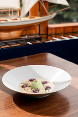 Fancy ice cream dessert with a scoop of pistachio ice cream, plums, almonds and creamy sauce, shot in a daylight