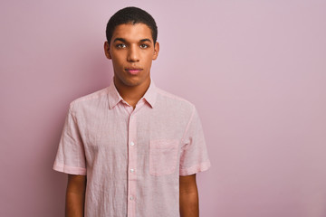 Young handsome arab man wearing casual shirt standing over isolated pink background Relaxed with serious expression on face. Simple and natural looking at the camera.