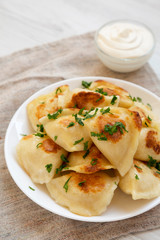 Homemade traditional polish fried potato pierogies on a white plate, low angle view. Closeup.