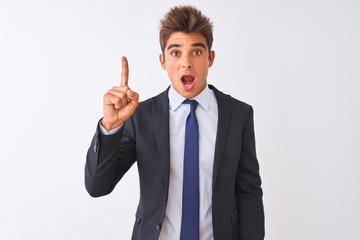 Young handsome businessman wearing suit standing over isolated white background pointing finger up with successful idea. Exited and happy. Number one.