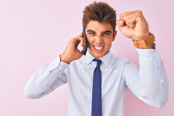 Young handsome businessman talking on the smartphone over isolated pink background annoyed and frustrated shouting with anger, crazy and yelling with raised hand, anger concept