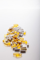 Tablets, pills, capsules, drugs pouring out of white bottle on white background. Sport, healthy lifestyle, medicine, nutritional supplements, people concept - closeup fish oil capsules soft gel