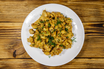 Stewed mushrooms with sour cream on wooden table. Top view