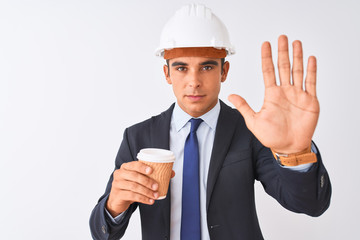 Young handsome architect man wearing helmet drinking coffee over isolated white background with open hand doing stop sign with serious and confident expression, defense gesture