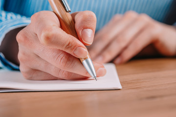 Beautiful Female hands write pen in a notebook of tasks and goals to work on a wooden table