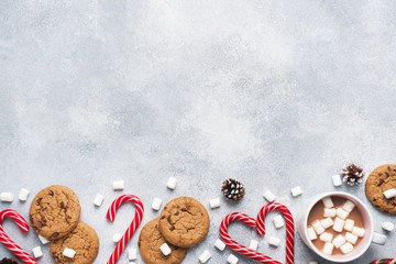 The chocolate chip cookie, Christmas cane caramel Cup cocoa and marshmallow cones Decorations on a gray background. Copy space Frame.