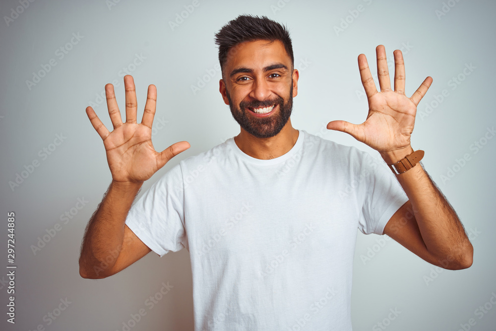 Sticker young indian man wearing t-shirt standing over isolated white background showing and pointing up wit