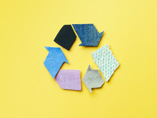 Reuse, reduce, recycle concept background. Recycle symbol made from old clothing on yellow...
