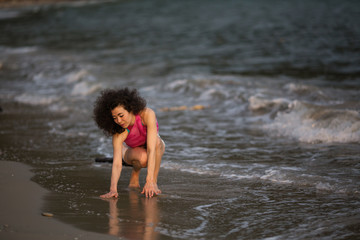 Fototapeta premium Young woman of mixed race in the waves on the surf line on the sea beach.