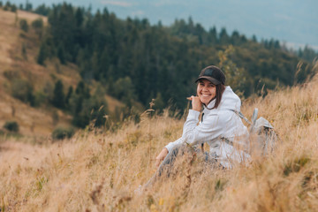 Naklejka na ściany i meble woman sitting on the ground looking at mountains hiking concept