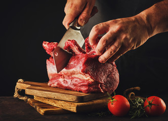 Male butcher cuts raw beef meat.